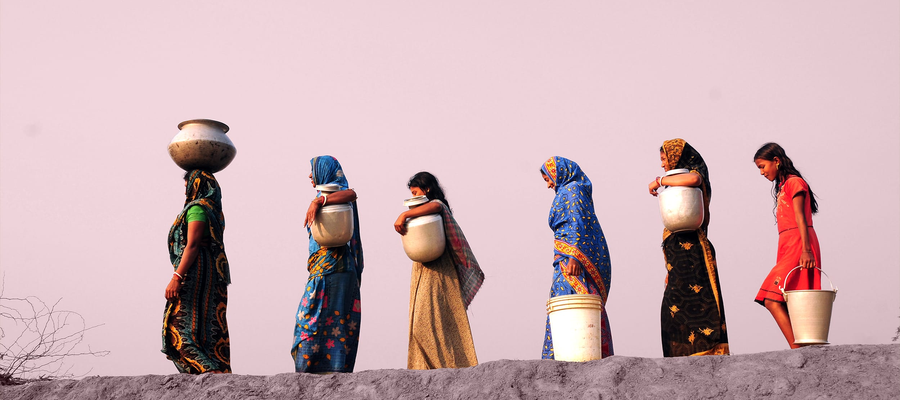 Women in Asia walk in a line carrying containers