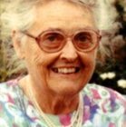 An older white woman with glasses smiles at the camera