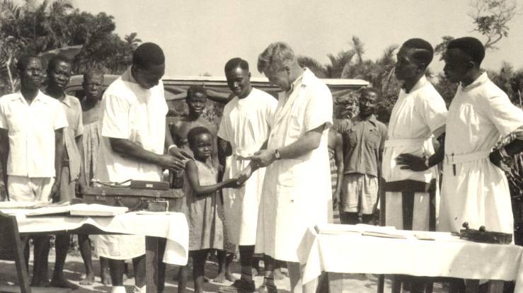 An outdoor clinic, probably Itu Nigeria. Showing patients being treated by missionary Dr Stanley Brown .png