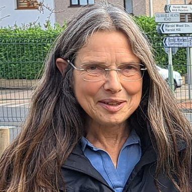 A woman with long hair and glasses looks at the camera