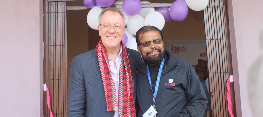 A man from Australia and a man from Nepal stand side by side in a doorway