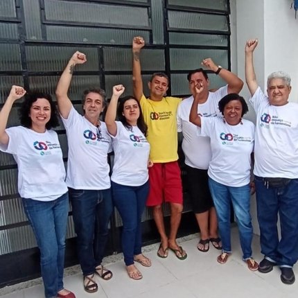 A group of seven adults from MORHAN in matching t-shirts stand with their hands raised in victory