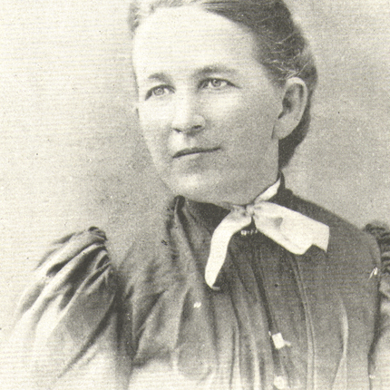 A black and white photo of a woman in an black dress with her hair pulled back