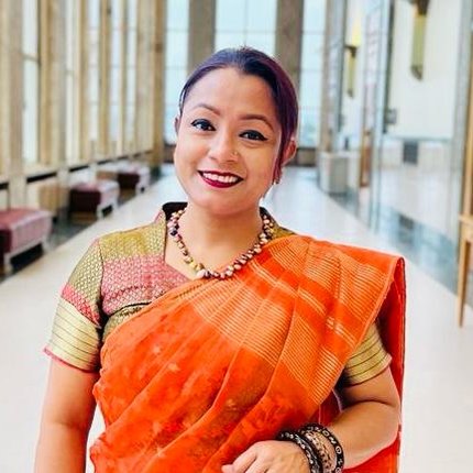 A woman from Bangladesh in bright orange clothing smiles at the camera