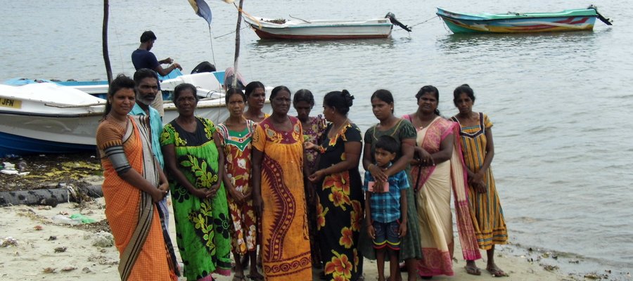 A group of Women from Sri Lanka smiling at the camera standing at the shore of a beach.