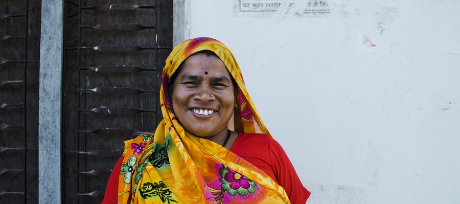 A woman in a colourful headscarf smiles at the camera