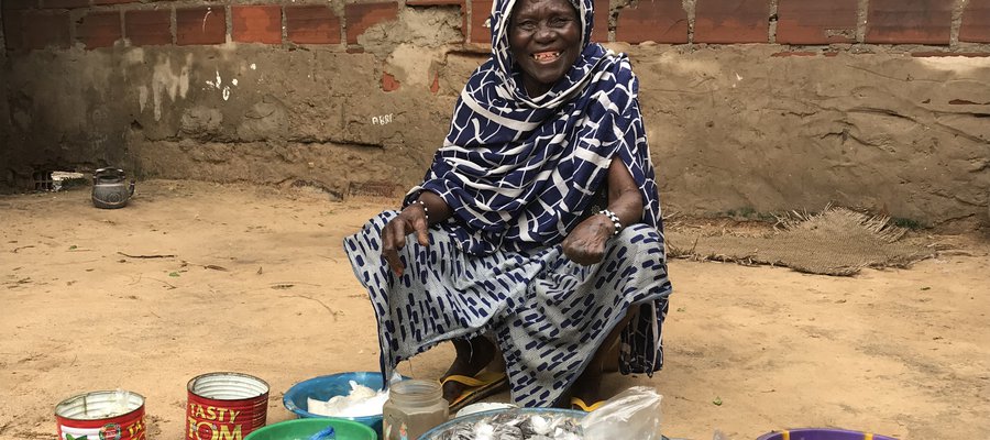 Hawa sits outside her home with the goods she is selling