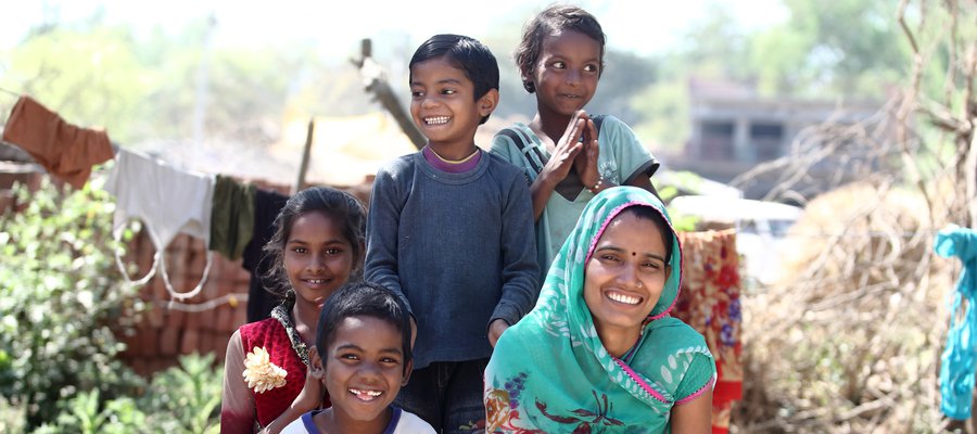 A woman and four children looking at the camera and smiling.