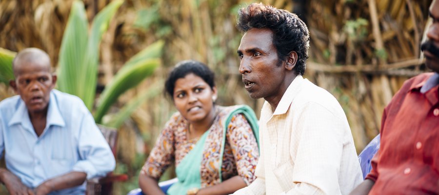 A man speaks to a group of people from his community