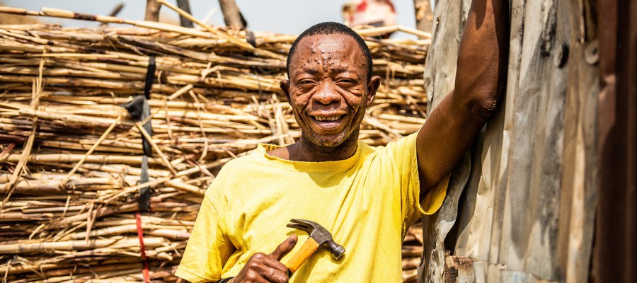 David in Nigeria pauses from working with a hammer to smile at the camera