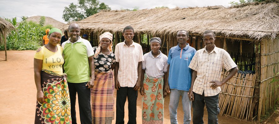 A group of people stand together, smiling in a village in Mozambique