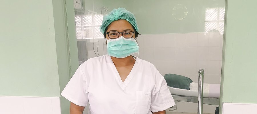 A lady stands in PPE in front of a surgical theatre