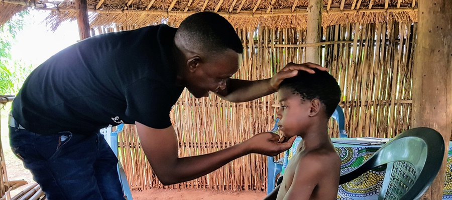 A man examines the face of a boy looking for signs of leprosy