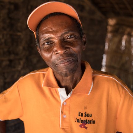 A man from Mozambique in an orange shirt which says 'eu sou voluntario' - I am a volunteer