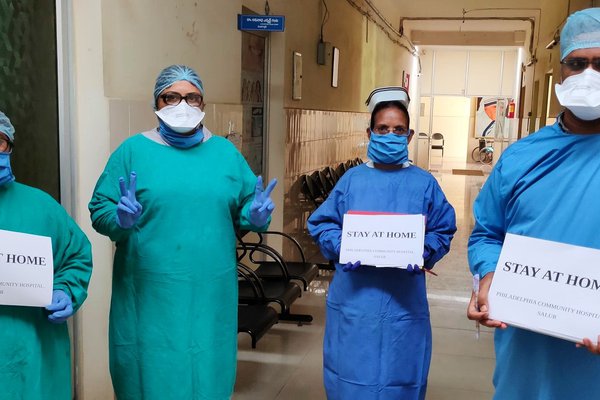 Doctors in PPE hold up 'Stay at home' signs