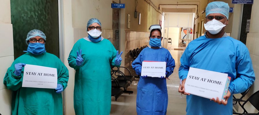 Doctors in PPE hold up 'Stay at home' signs