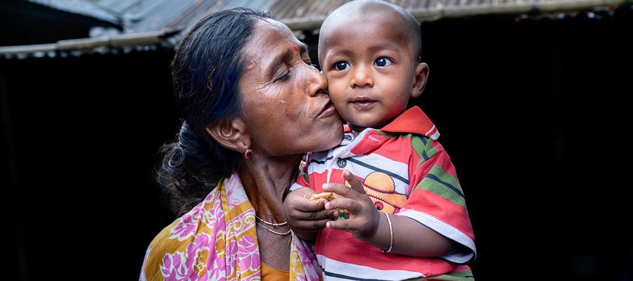 Sudha holds her infant grandson and gives him a kiss on the cheek