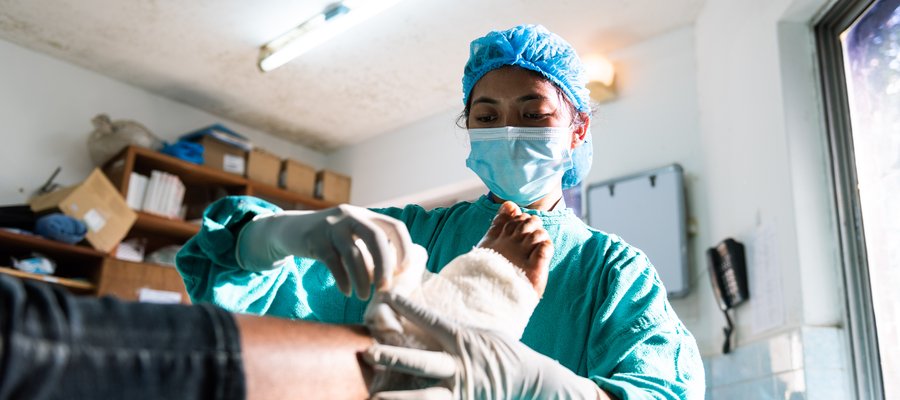 A medical professional in surgical clothing dresses a wound