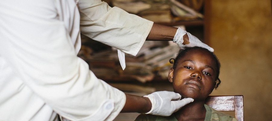 The photo is focused on a girl's face as she is examined by a doctor