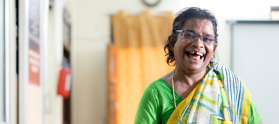 A woman with a cane smiling at the camera.