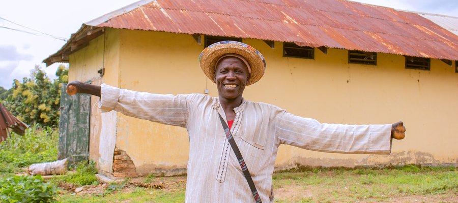 A man from Nigeria with a hat on smiling at the camera.