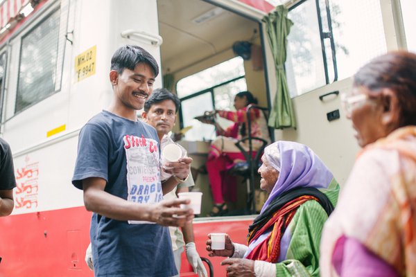 Karuna Mobile Clinic - people share cups of chai together at the clinic