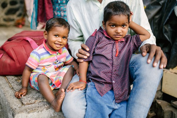Two young children sit with their father in India