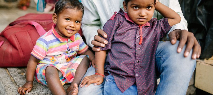 Two young children sit with their father in India