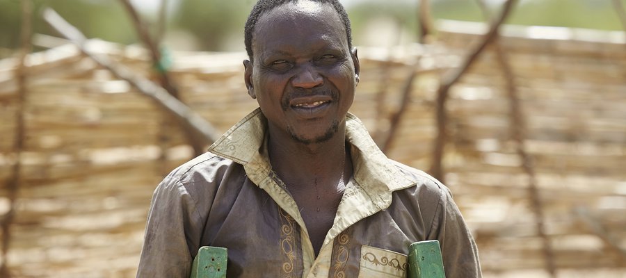 Lau, a person affected by leprosy, stands on his crutches looking at the camera