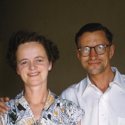 A man and woman in white clothes, both with brown hair and the man is wearing glasses