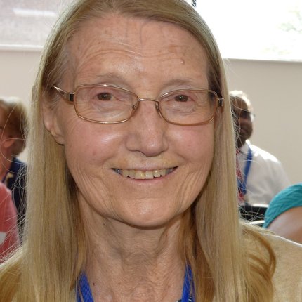 A woman with light hair and glasses smiles at the camera