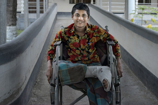 A younger boy in a wheelchair smiling at the camera.