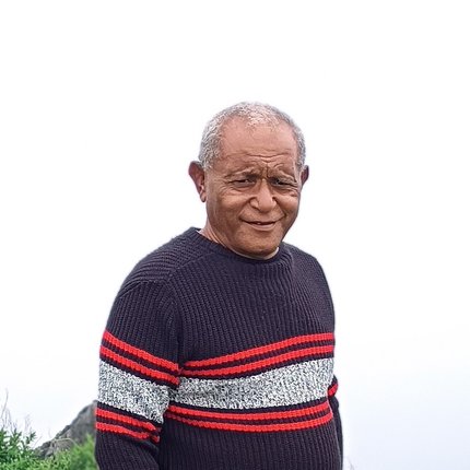 A middle-aged man from Indonesia wears a sweater and looks to camera