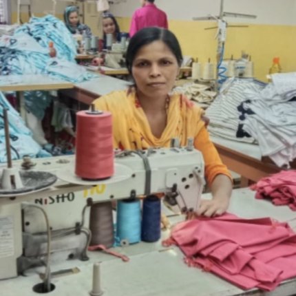 Woman wearing a yellow shirt sits in front of a sewing machine