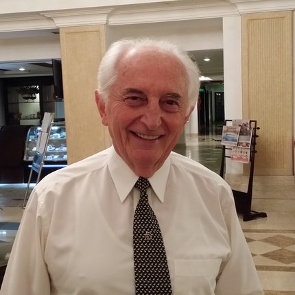 A man in a shirt and tie smiles at the camera in a reception area